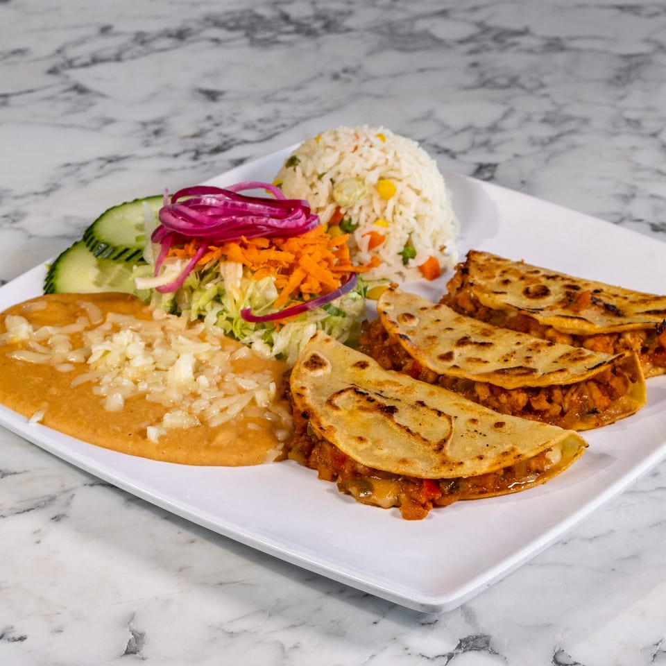 Mexican plate with three quesadillas, refried beans, rice, salad, and cucumber slices.