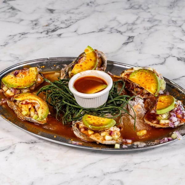 Mexican oysters topped with avocado, red onion, and cucumber, served with a spicy sauce.